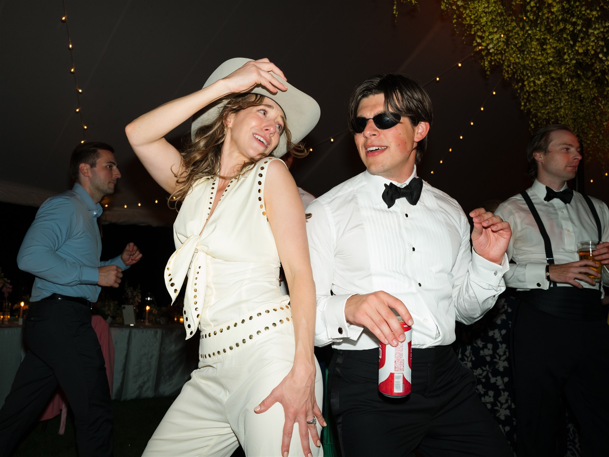 Katherine and Henry dancing side-by-side on the dance floor at their Lake Minnetonka wedding, with Katherine wearing Henry’s cowboy hat and her second wedding outfit.